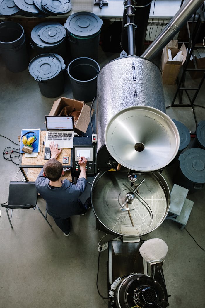 Overhead view of a man using laptop and equipment in a coffee roastery.